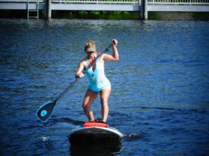 Fitness trainer demonstrating strength and balance exercises on a paddleboard